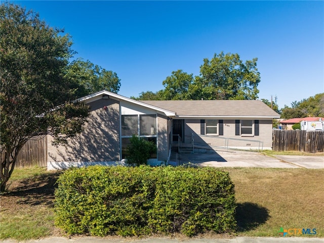 view of front of house with a front yard, a sunroom, brick siding, and fence