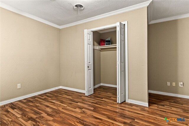 unfurnished bedroom featuring visible vents, baseboards, wood finished floors, crown molding, and a closet