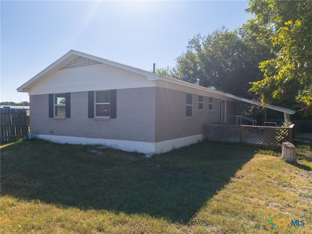 view of side of property with brick siding, a yard, and fence