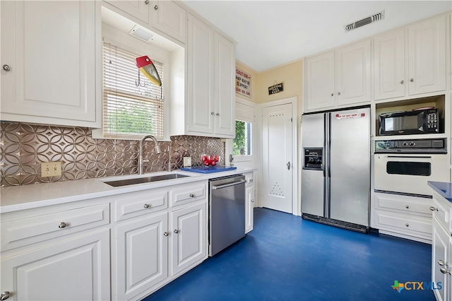 601 Lakewood Dr, Burnet, TX 78611 - kitchen with backsplash, visible vents, a sink, stainless steel appliances, and white cabinetry