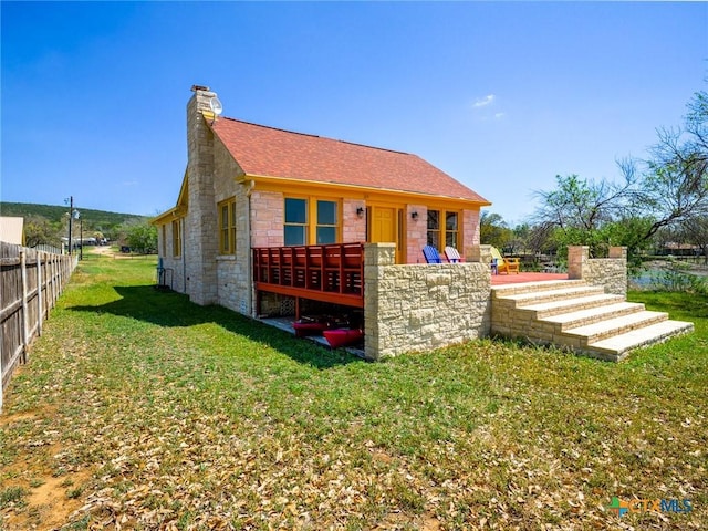 601 Lakewood Dr, Burnet, TX 78611 - view of front of property featuring a chimney, a front yard, fence, a shingled roof, and stone siding