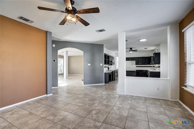 unfurnished living room with ceiling fan, a healthy amount of sunlight, and light tile patterned floors