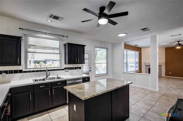 kitchen with backsplash, a center island, ceiling fan, and sink