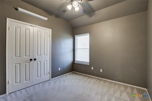 unfurnished bedroom featuring ceiling fan, a closet, light carpet, and vaulted ceiling