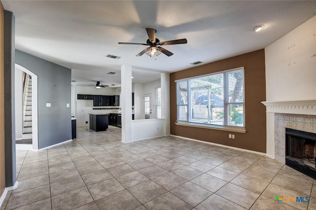 unfurnished living room with tile patterned floors, ceiling fan, and a fireplace