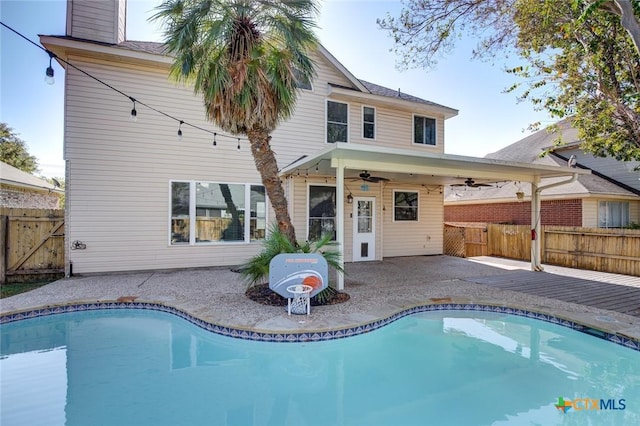 back of property with a patio, a fenced in pool, and ceiling fan