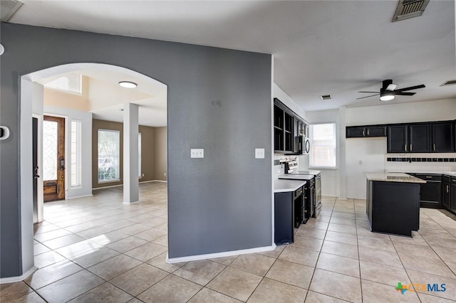 kitchen featuring a center island, stainless steel electric range, a healthy amount of sunlight, and tasteful backsplash