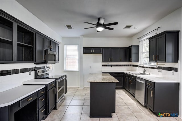 kitchen featuring ceiling fan, sink, backsplash, a kitchen island, and appliances with stainless steel finishes