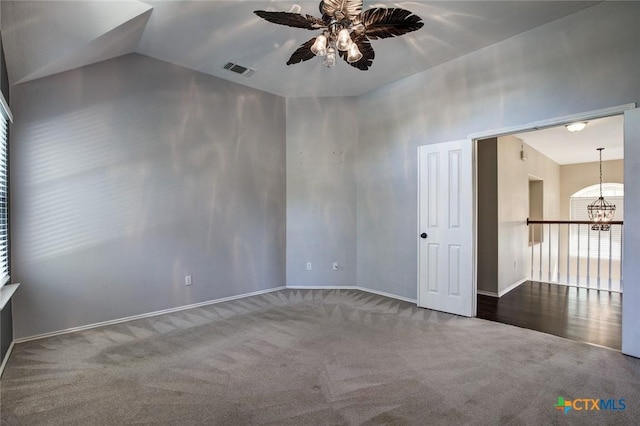 unfurnished room with ceiling fan with notable chandelier, carpet floors, and vaulted ceiling