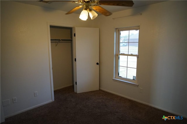 unfurnished bedroom with a closet, dark carpet, and ceiling fan