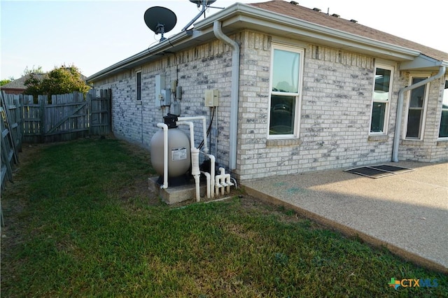 view of side of home with a lawn and a patio