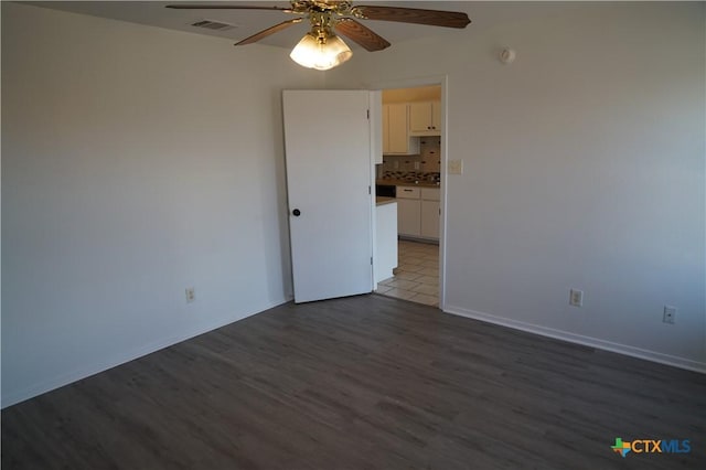 empty room with ceiling fan and dark hardwood / wood-style floors