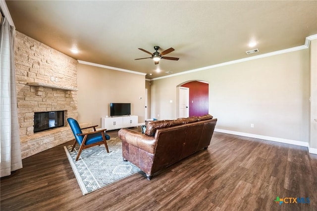 living room with dark wood-style floors, visible vents, baseboards, arched walkways, and a stone fireplace