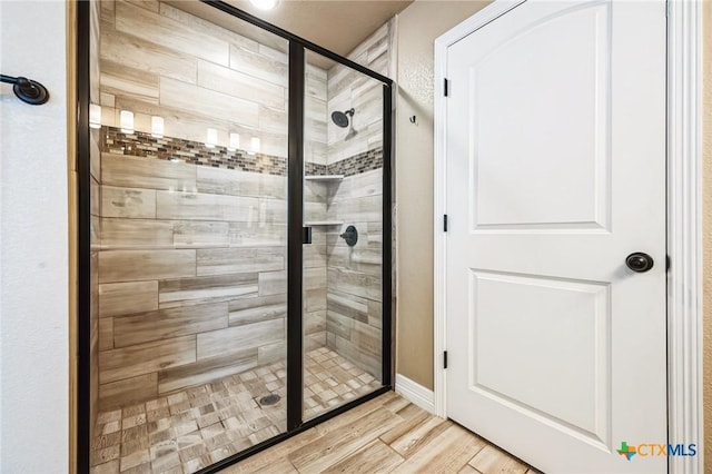 bathroom with a shower stall and wood finished floors