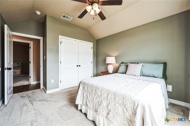 carpeted bedroom with lofted ceiling, baseboards, visible vents, and a closet