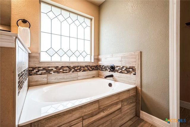 bathroom with a garden tub and a textured wall