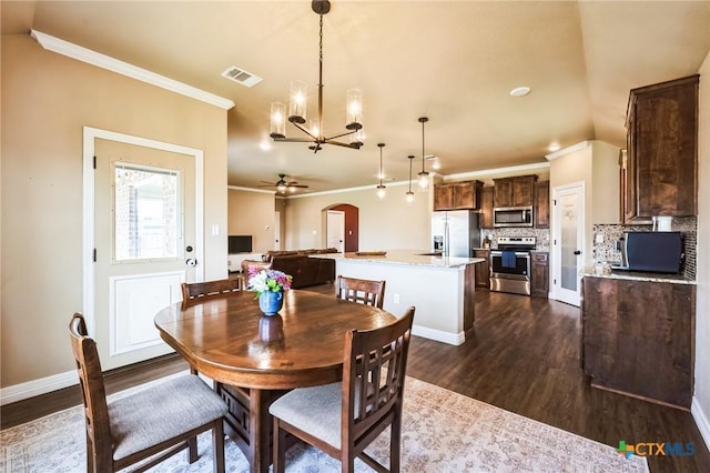 dining room featuring baseboards, dark wood-style floors, arched walkways, and ornamental molding