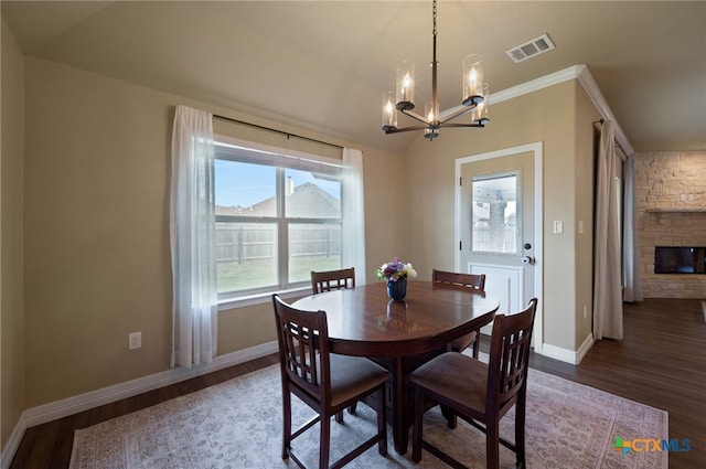 dining room with a fireplace, wood finished floors, visible vents, and baseboards