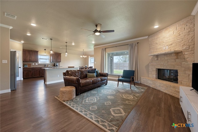 living area featuring dark wood-type flooring, a healthy amount of sunlight, and crown molding