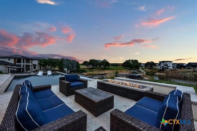 patio terrace at dusk featuring an outdoor living space with a fire pit and a water view