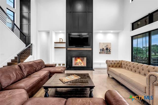 117 Legendary Estates Dr, Burnet, TX 78611 - living area with a high ceiling, a fireplace, stairway, concrete flooring, and built in features
