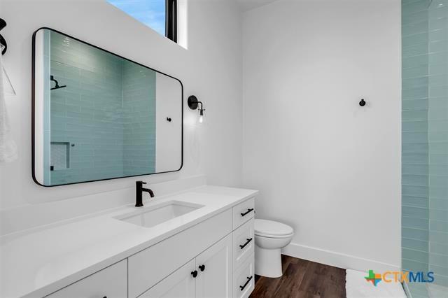 117 Legendary Estates Dr, Burnet, TX 78611 - full bathroom featuring vanity, toilet, tiled shower, and wood finished floors