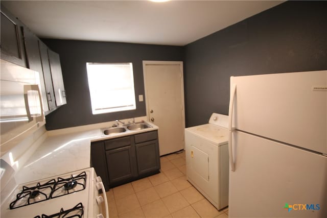 kitchen with white appliances, sink, light tile patterned floors, and washer / dryer