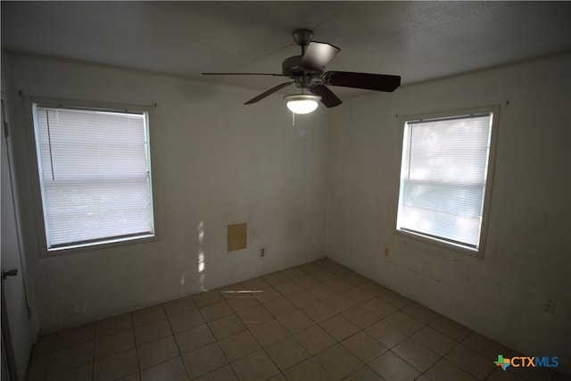 tiled empty room featuring ceiling fan