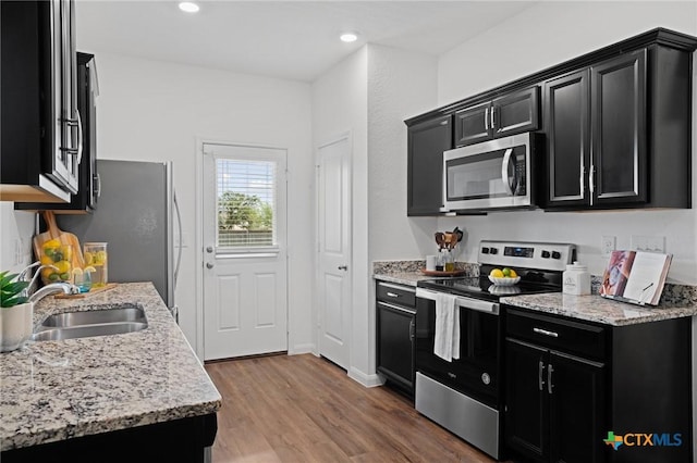 5806 Gulf Mdw, Converse, TX 78109 - kitchen featuring stainless steel appliances, dark cabinets, wood finished floors, light stone counters, and recessed lighting
