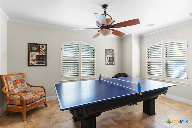 rec room with light tile patterned flooring, a wealth of natural light, ceiling fan, and crown molding