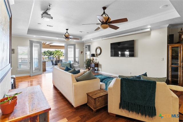 living room with hardwood / wood-style floors, a textured ceiling, ceiling fan, crown molding, and a tray ceiling