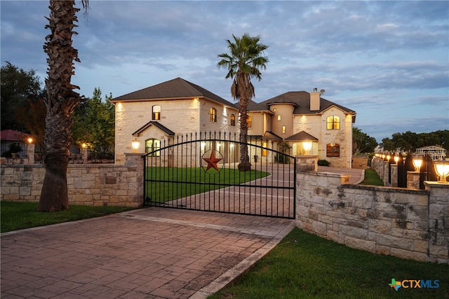 gate at dusk featuring a lawn