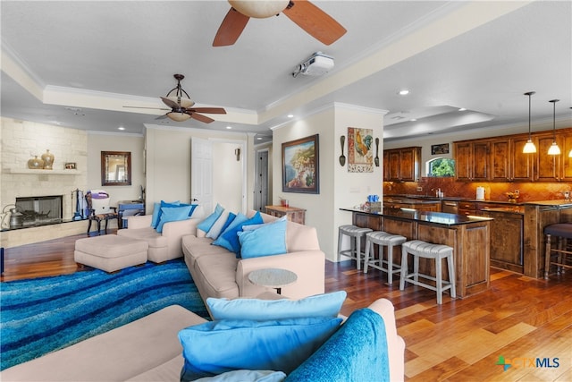 living room with ornamental molding, dark hardwood / wood-style floors, a raised ceiling, and ceiling fan