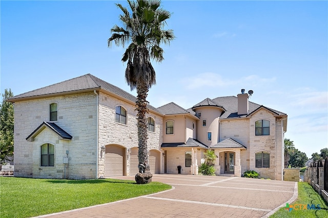 french country style house featuring a garage and a front lawn