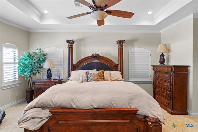 carpeted bedroom with a raised ceiling, ceiling fan, and crown molding