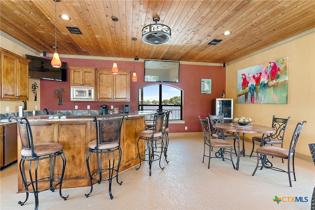 kitchen with stainless steel microwave, a kitchen breakfast bar, decorative light fixtures, and wooden ceiling