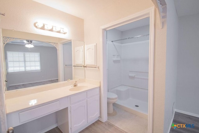 full bathroom featuring vanity, toilet, a ceiling fan, baseboards, and a shower