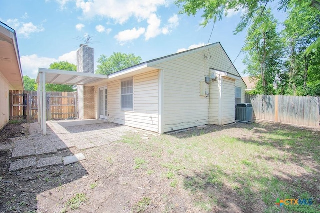 back of house featuring a patio, a fenced backyard, central AC, and a chimney