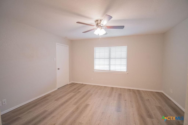 spare room featuring light wood-type flooring, baseboards, and ceiling fan