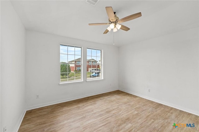 spare room featuring wood finished floors, visible vents, baseboards, and ceiling fan