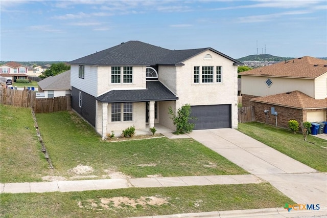 traditional-style home featuring fence, an attached garage, a front yard, and concrete driveway