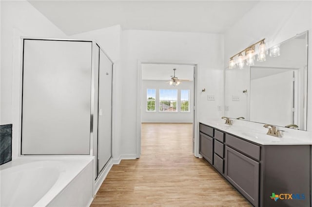 full bath featuring a garden tub, a sink, wood finished floors, a stall shower, and double vanity