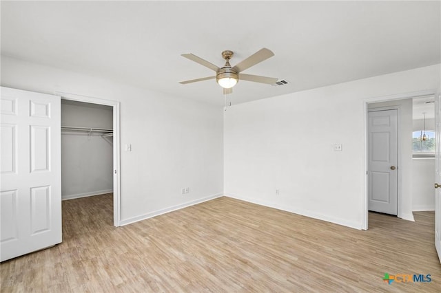 unfurnished bedroom featuring a spacious closet, baseboards, visible vents, and light wood-style flooring