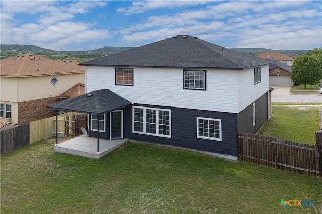 rear view of property featuring a fenced backyard, a patio area, a lawn, and roof with shingles