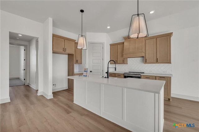 kitchen with stainless steel range with electric cooktop, an island with sink, backsplash, hanging light fixtures, and light hardwood / wood-style flooring