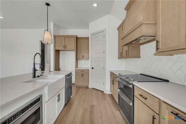 kitchen with light hardwood / wood-style floors, appliances with stainless steel finishes, decorative backsplash, pendant lighting, and light brown cabinets