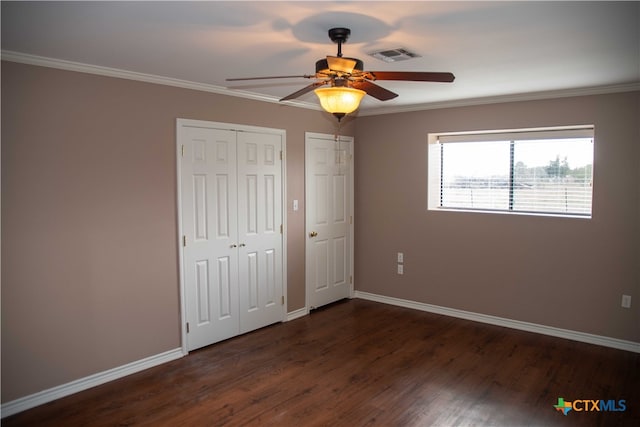 unfurnished bedroom featuring ornamental molding, dark wood finished floors, visible vents, and baseboards