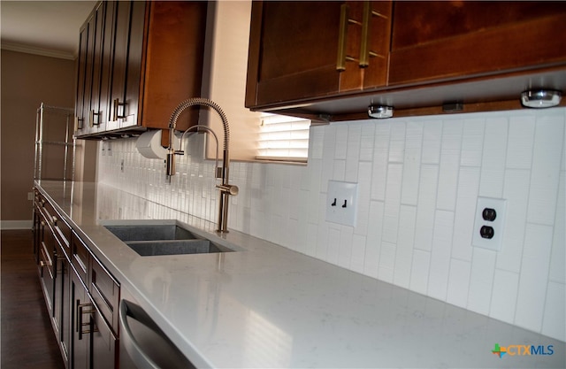 kitchen featuring dark wood-style floors, ornamental molding, light stone counters, a sink, and backsplash