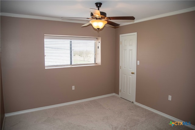 unfurnished room with ornamental molding, light colored carpet, baseboards, and a ceiling fan