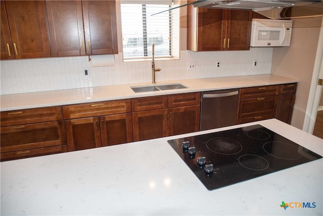 kitchen with white microwave, black electric cooktop, light countertops, stainless steel dishwasher, and a sink